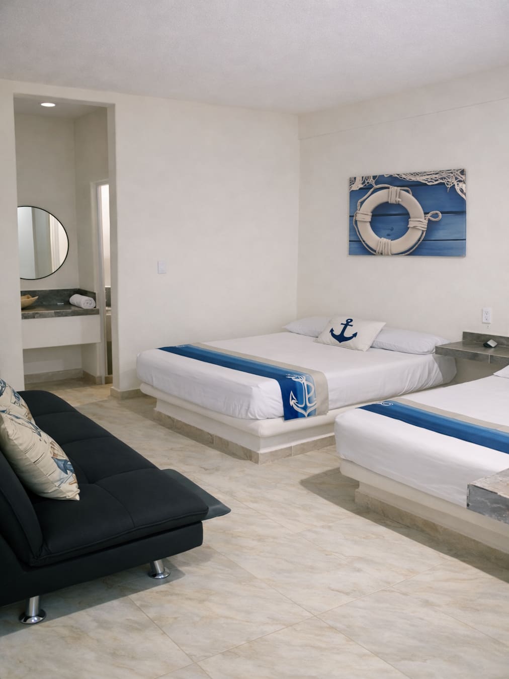Vista de una de las camas dobles, sofá cama, acceso al baño,  decoración y buró de la habitación Triple 5 – Casa Tania